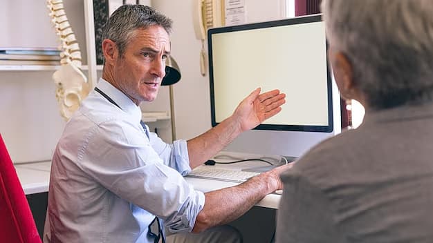 Fysiotherapeut legt tijdens de intake iets uit aan een patiënt achter het bureau