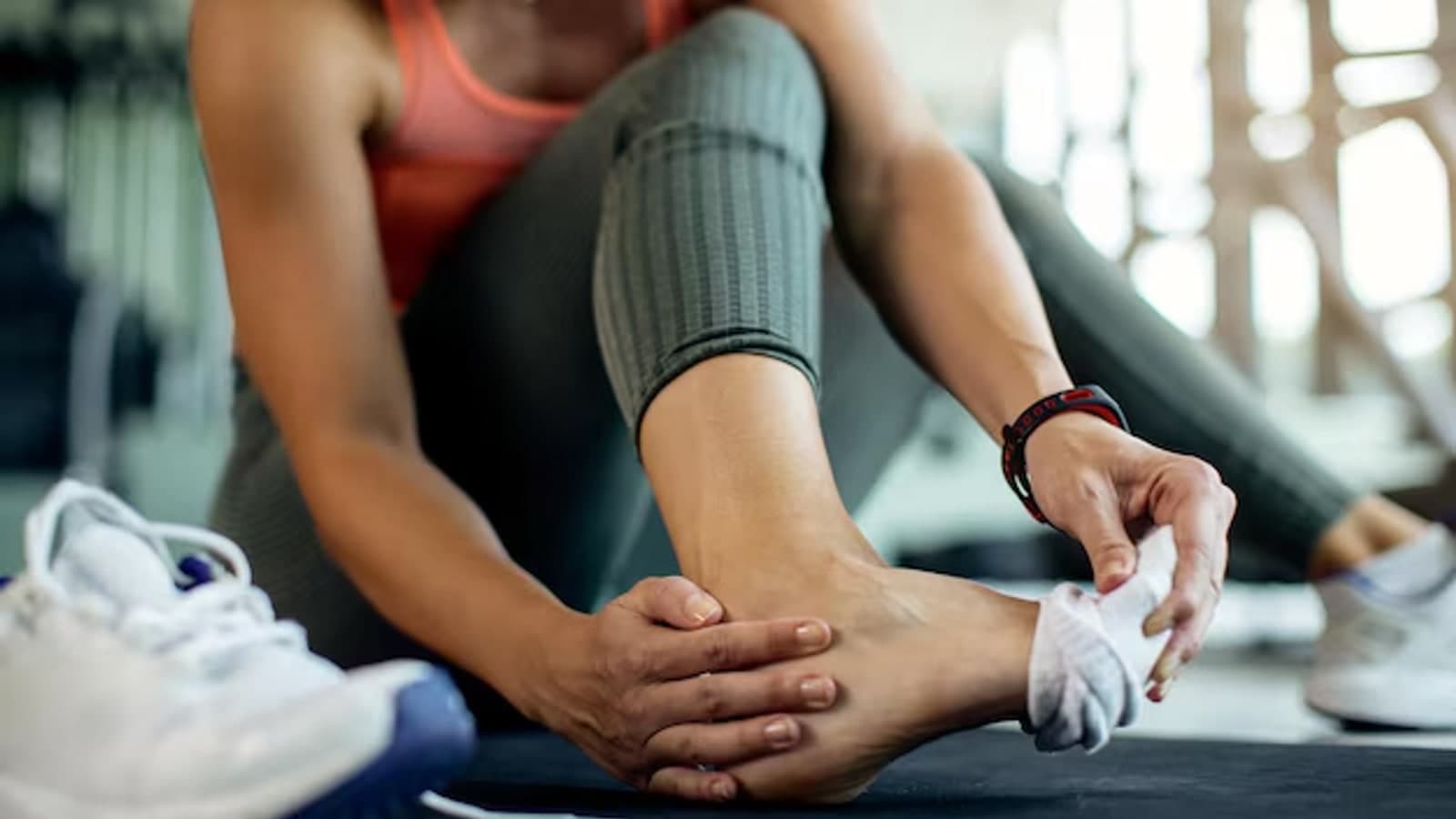 Sporter in de sportschool bekijkt de enkel na een blessure tijdens de training