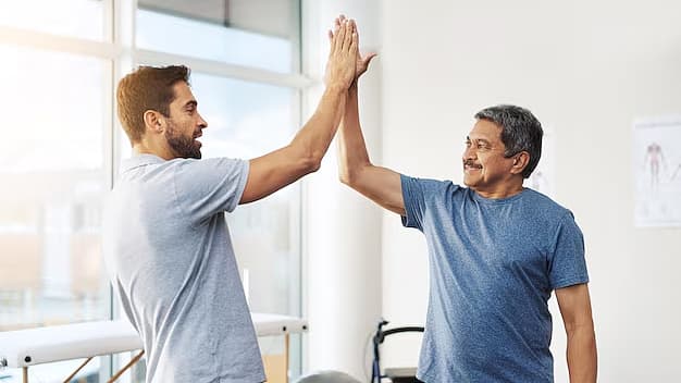 Fysiotherapeut en patiënt geven elkaar een high-five in de behandelruimte