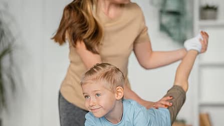 Kinderfysiotherapeut begeleidt een jongen bij oefeningen op de mat