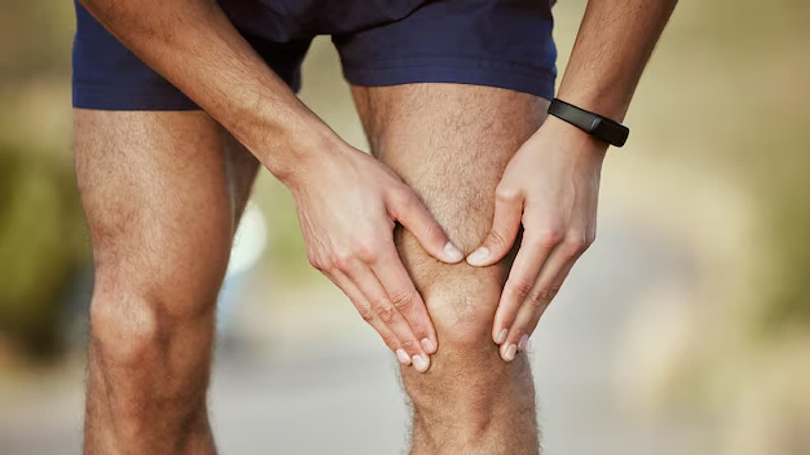 Hardloper houdt met beide handen de knie vast vanwege pijn tijdens het sporten